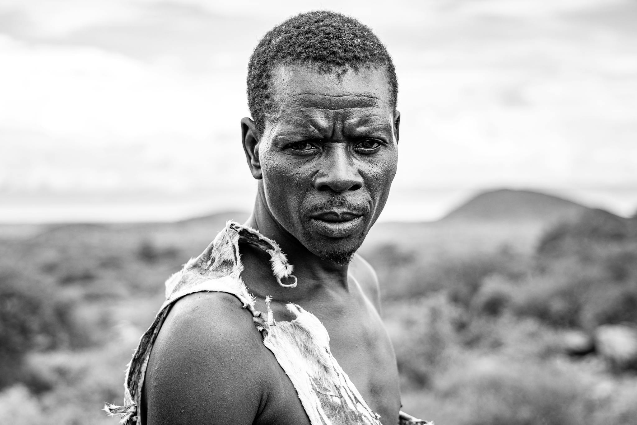 Powerful black and white portrait capturing a man's intense gaze outdoors.
