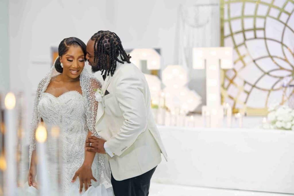 Bride and groom at Nigerian wedding dancing with guests under colorful lights