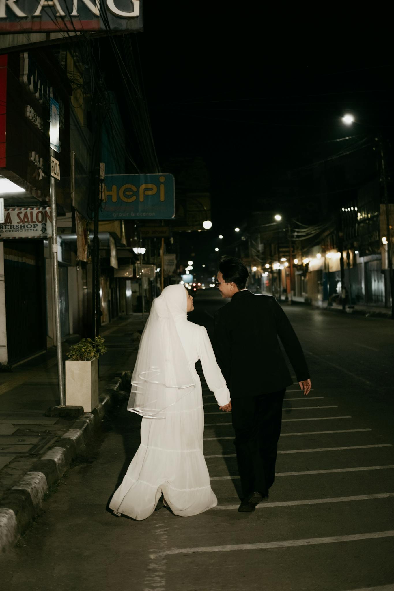 A Muslim couple enjoys a romantic walk in the city at night, capturing love and togetherness.