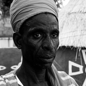 Black and white portrait of a Nigerian man in traditional attire.