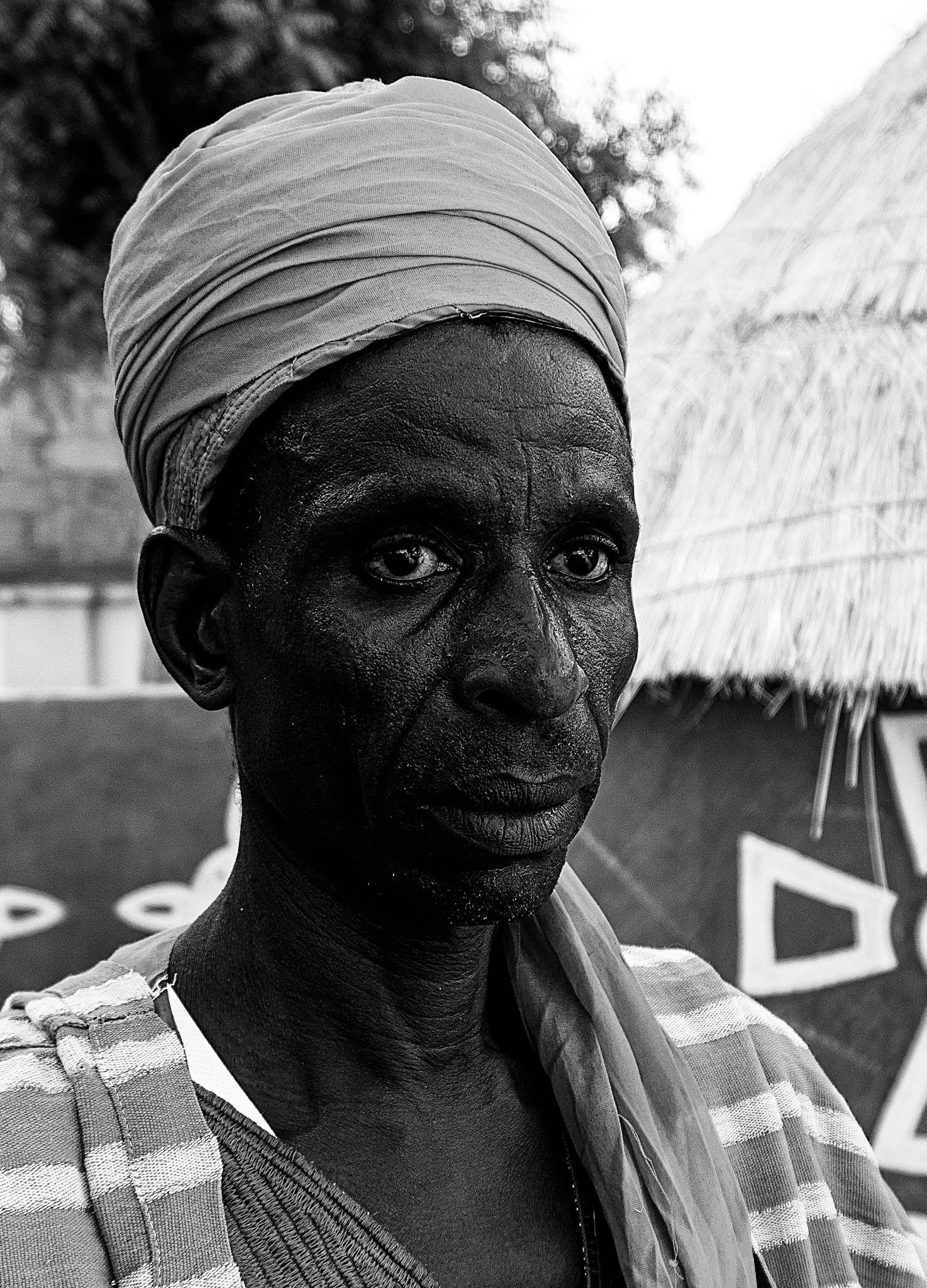 Black and white portrait of a Nigerian man in traditional attire.