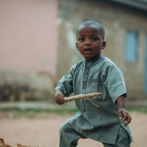 Charming portrait of a young child playing outside in Kaduna, Nigeria. Capturing cultural essence and innocence.