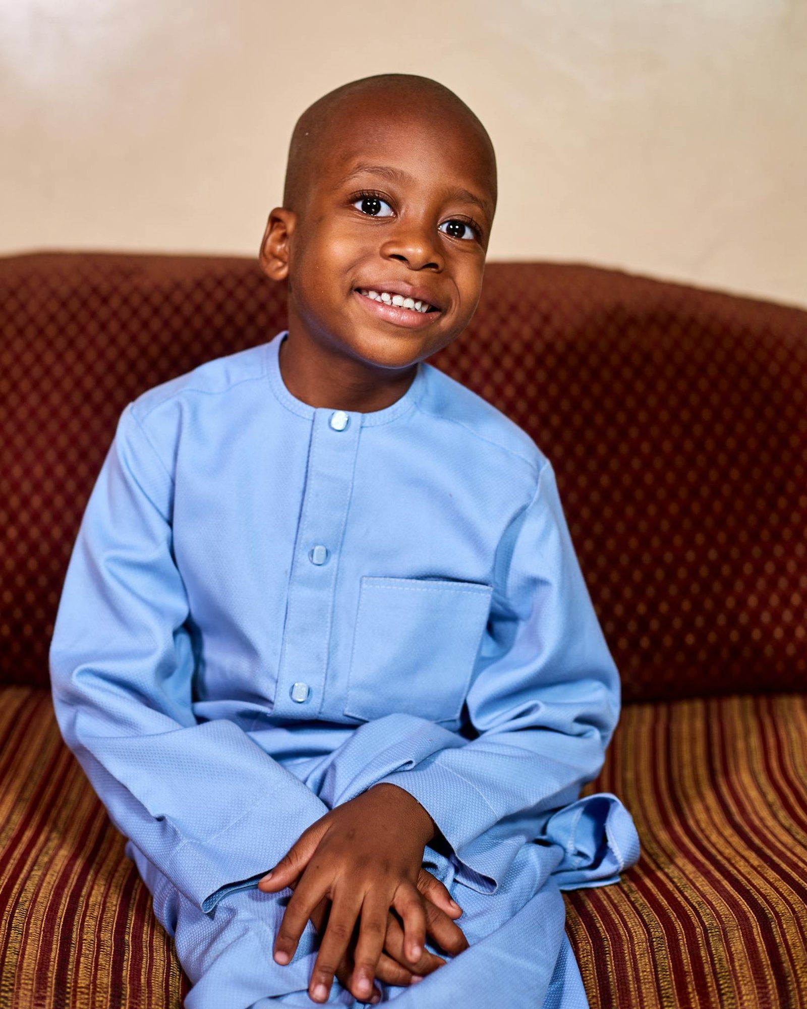 Charming portrait of a young Nigerian boy dressed in blue traditional attire, smiling warmly.