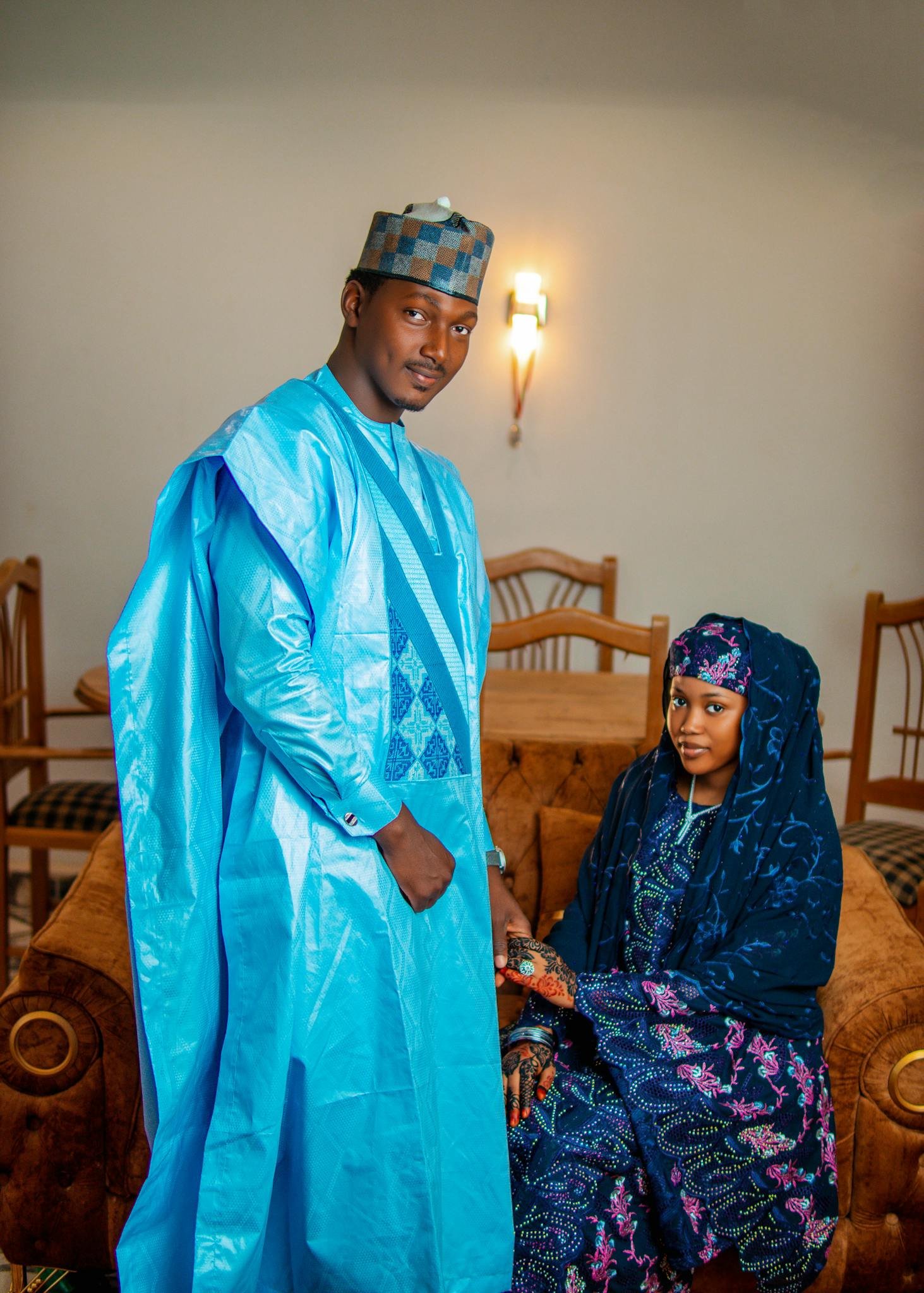 Elegant couple in vibrant Nigerian attire indoors, capturing cultural essence.