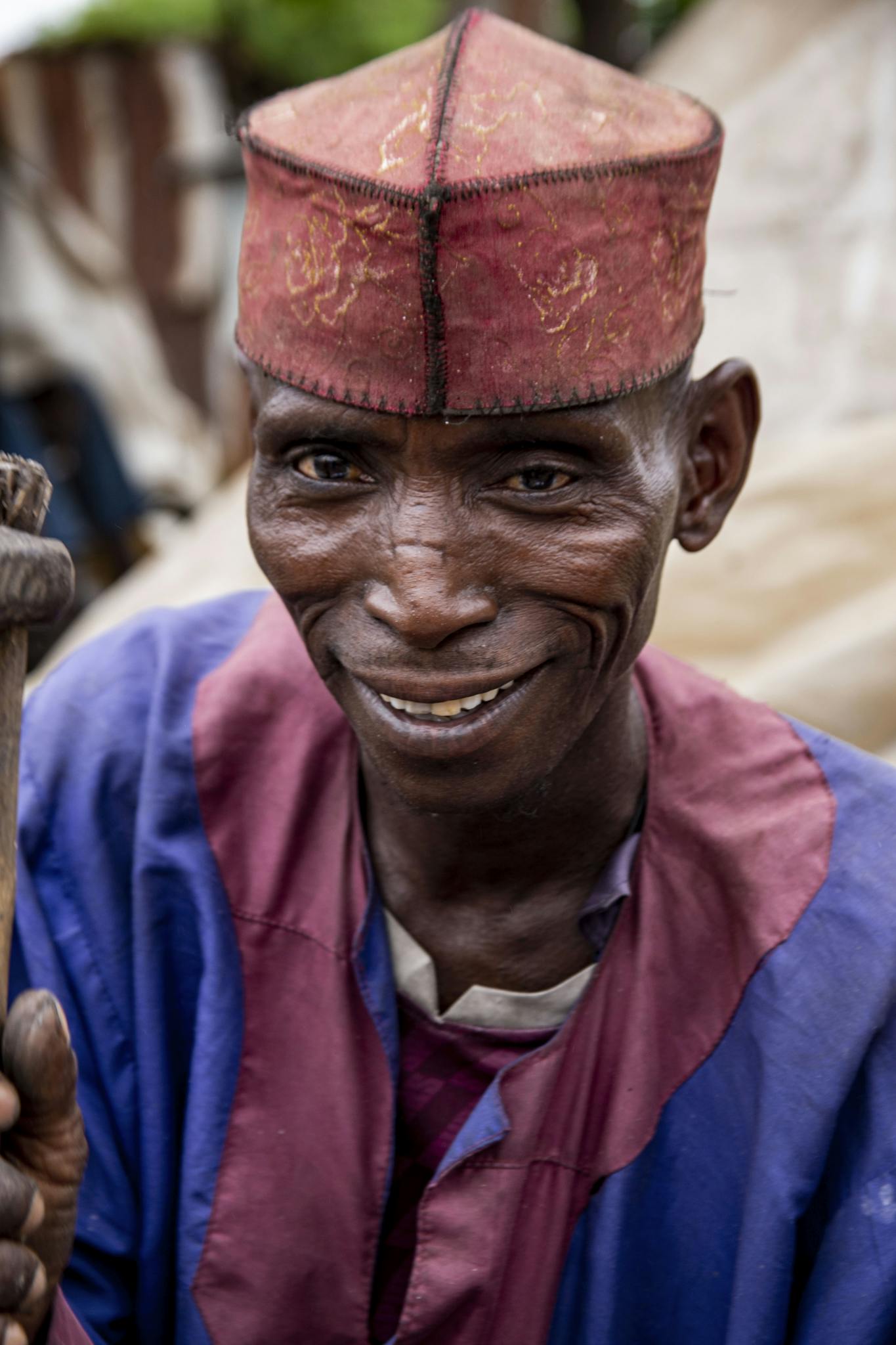 Portrait of a joyful man in Kaduna, Nigeria, wearing traditional attire and cap.